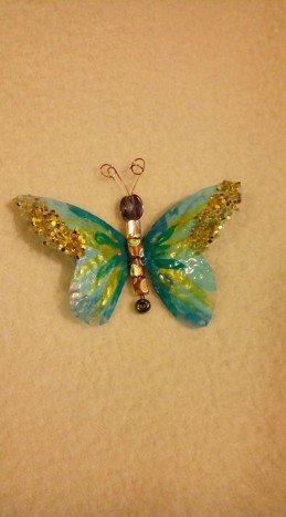 Zlati prah na metuljčku - Z lakom za nohte narisan metuljček na košček plastike. Na krilih prah zlate barve